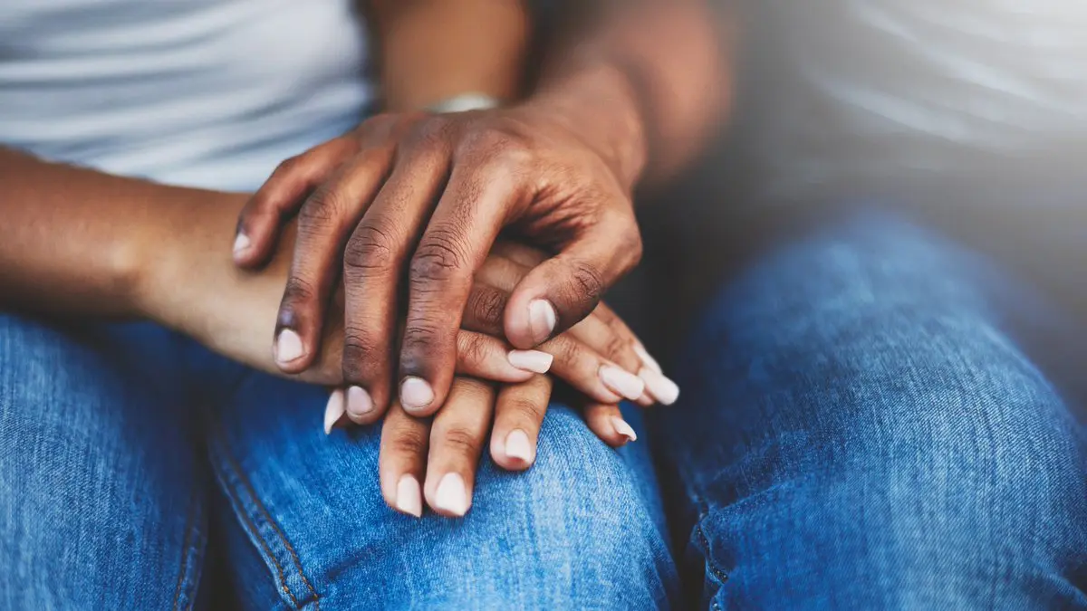 Hands held together supportively on a persons knee