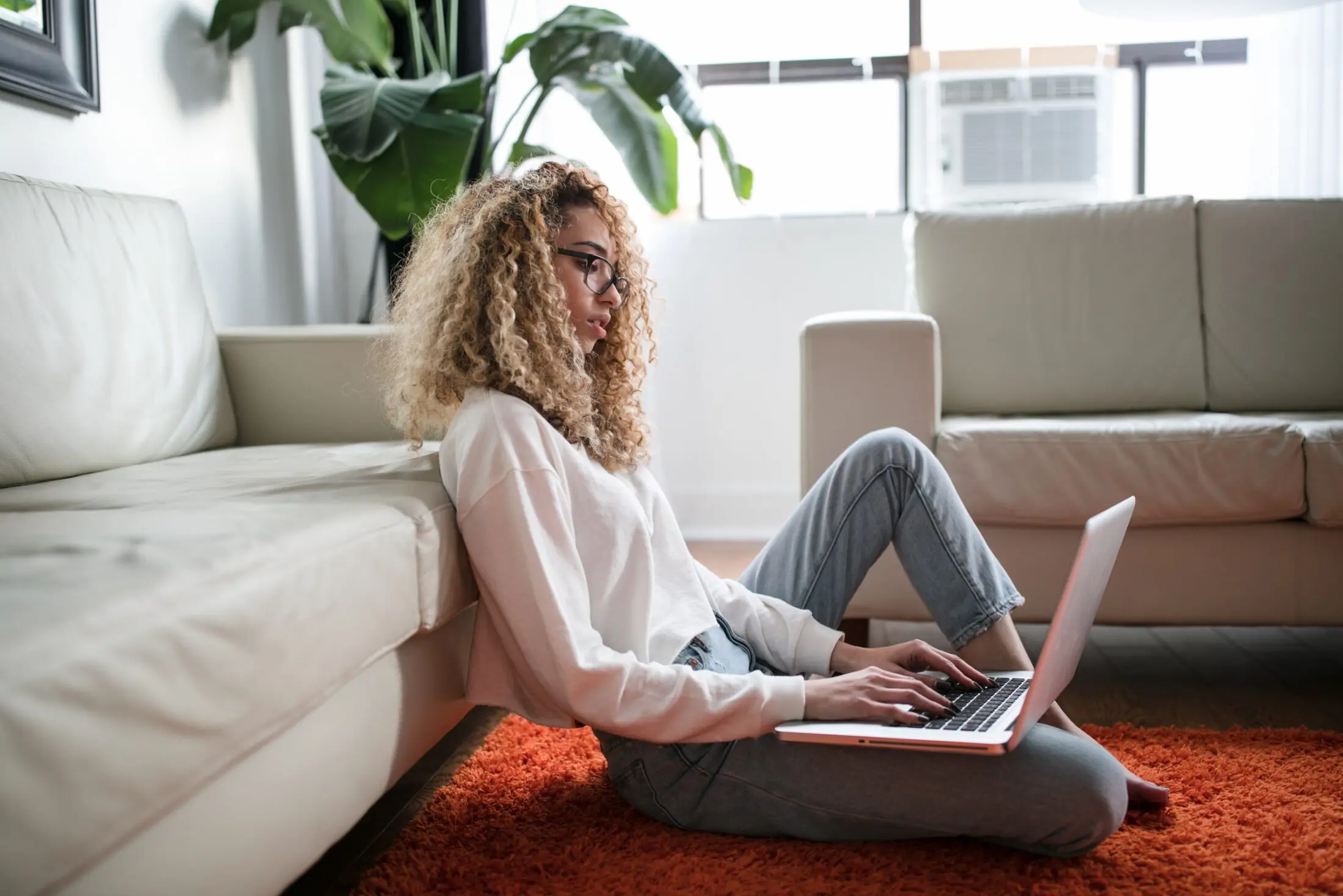 Young women sitting on the floor typing on laptop