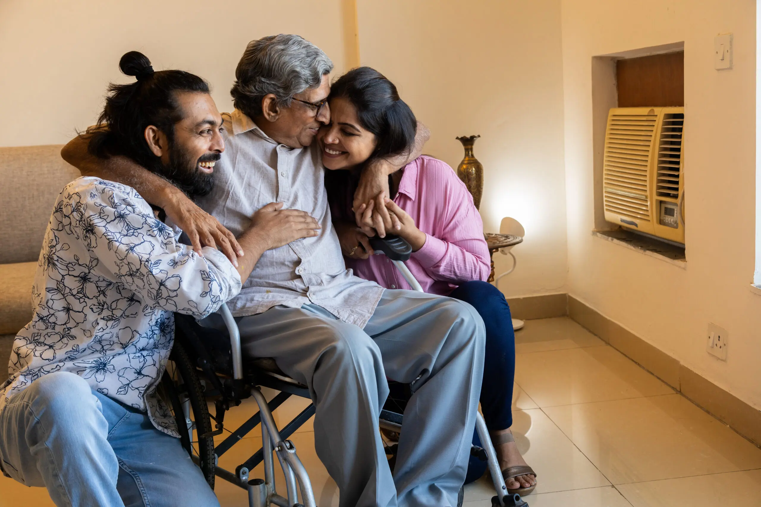 Happy young people spending time with disabled person in wheelchair at home