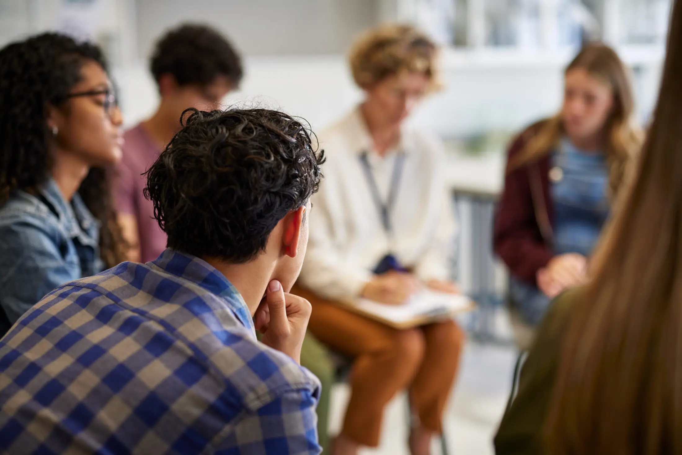 Young people sitting in a circle with adult making notes