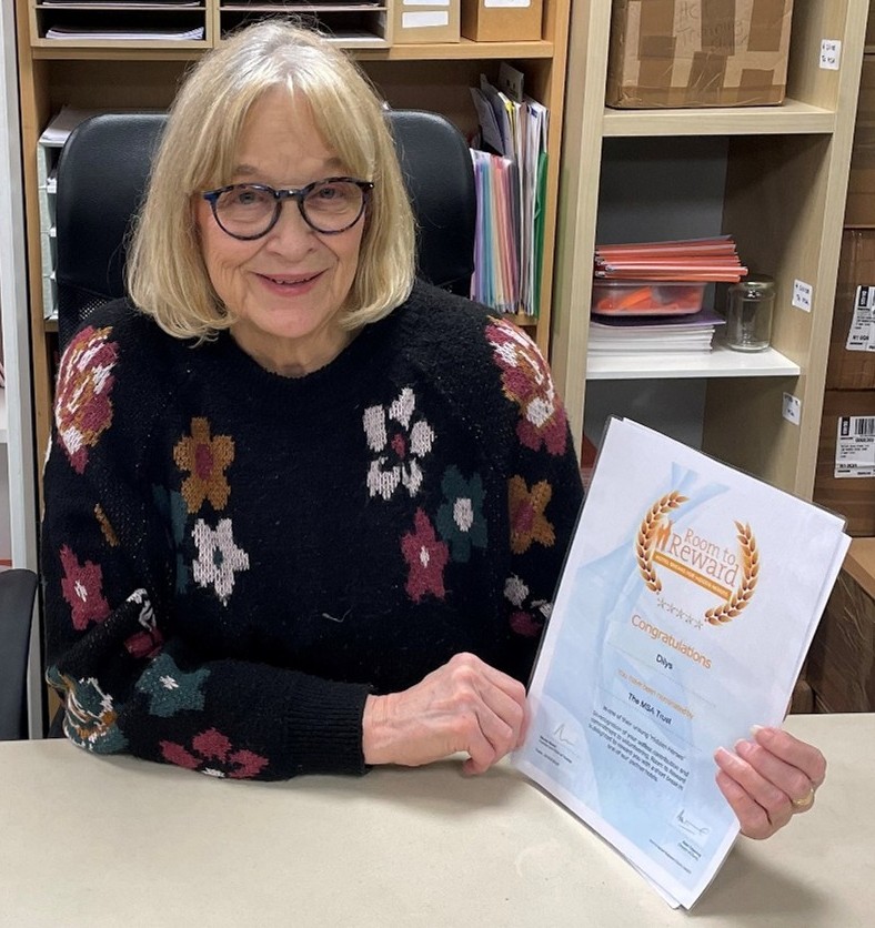 A female volunteer behind a desk, holding a document