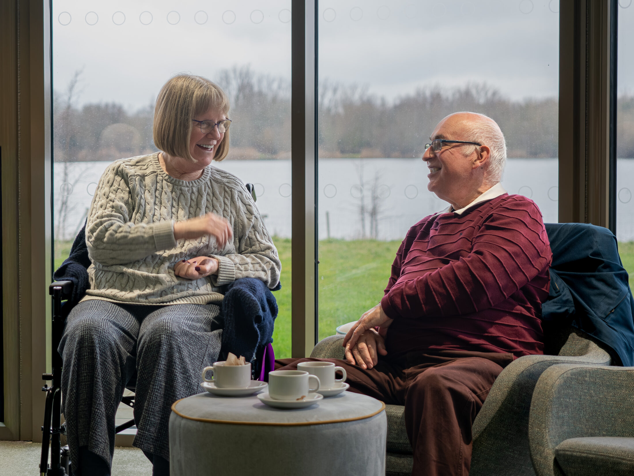 A man and a women talking, one person is using a wheelchair. 