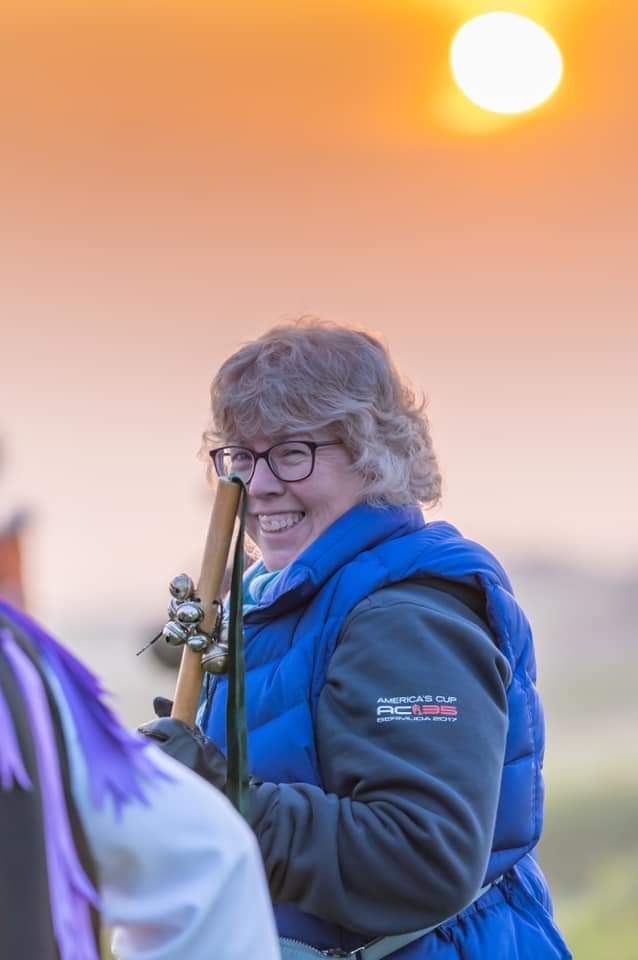 Woman smiling at camera, in front of a sky at sunrise